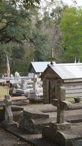 cemetery with cement graves in the foreground and historic grave houses in the background