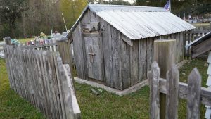 historic grave house built over an old grave, enclosed by a wooden picket fence