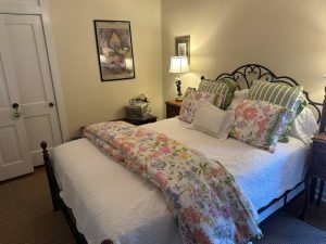 neatly made-up bed with flowered blanket across the top
