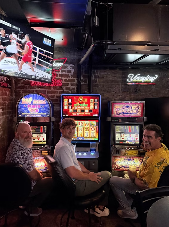 Three men sitting at video poker machines