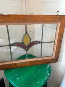 Stained glass window pane featuring a flower perched on a green stool