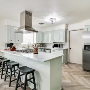 kitchen with mint green cabinets and stainless steel appliances, barstools in the front