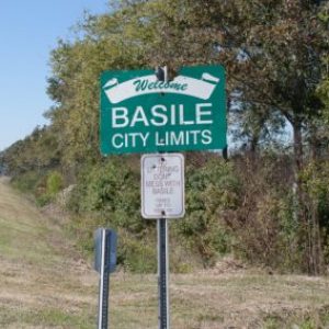 green sign on the side of the road, reads Basile City Limits